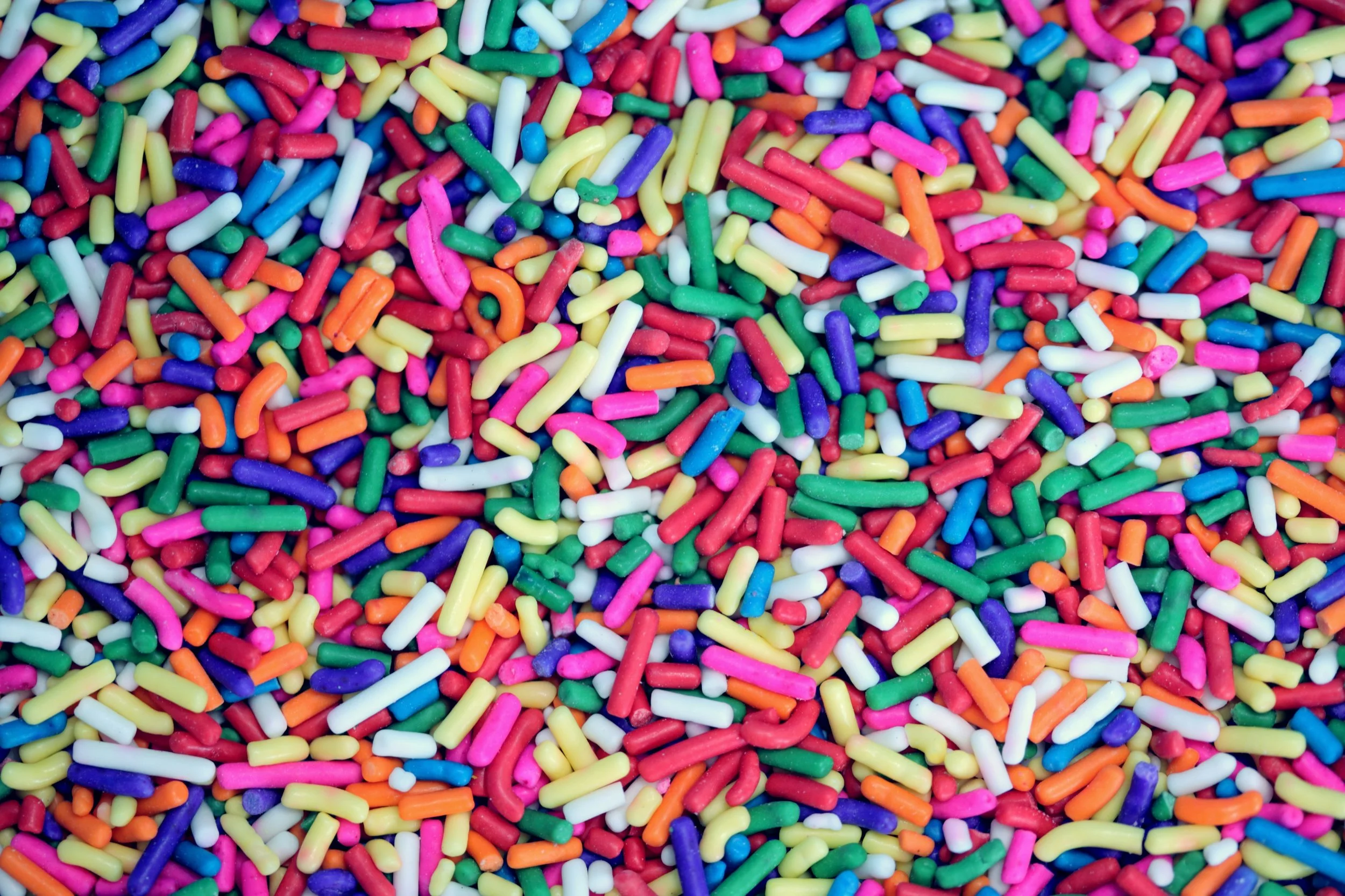Colorful rainbow sprinkles scattered together.