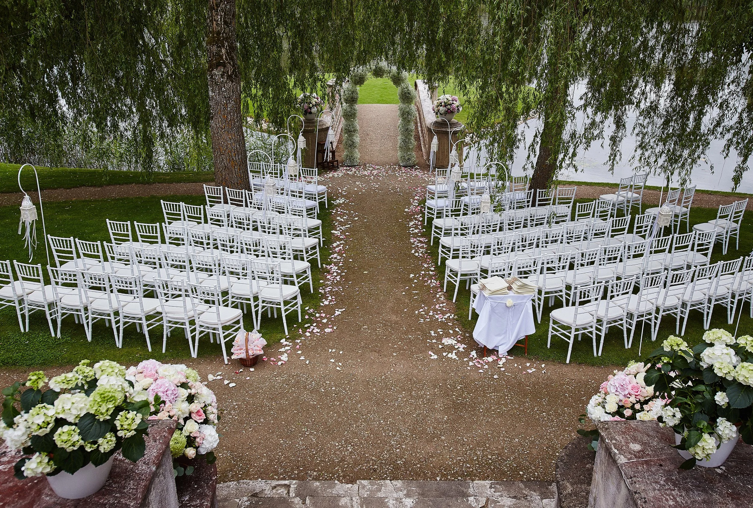 place-wedding-ceremony-with-wedding-arch-decorated-with-flowers-white-chairs-each-side-archway-outdoors-preparation-wedding-ceremony-outdoors-near-lake.jpg