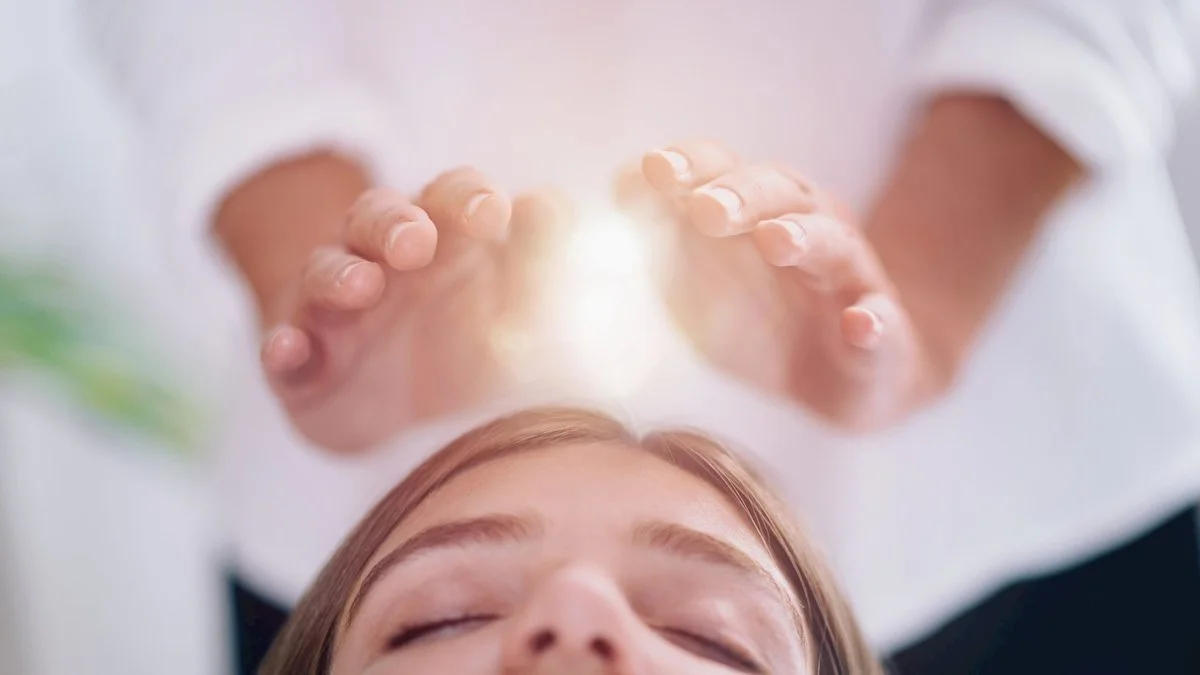 Une personne recevant une séance de reiki ou d'énergie, ses mains sont positionnées au-dessus de sa tête, émettant de la lumière et de l'énergie.