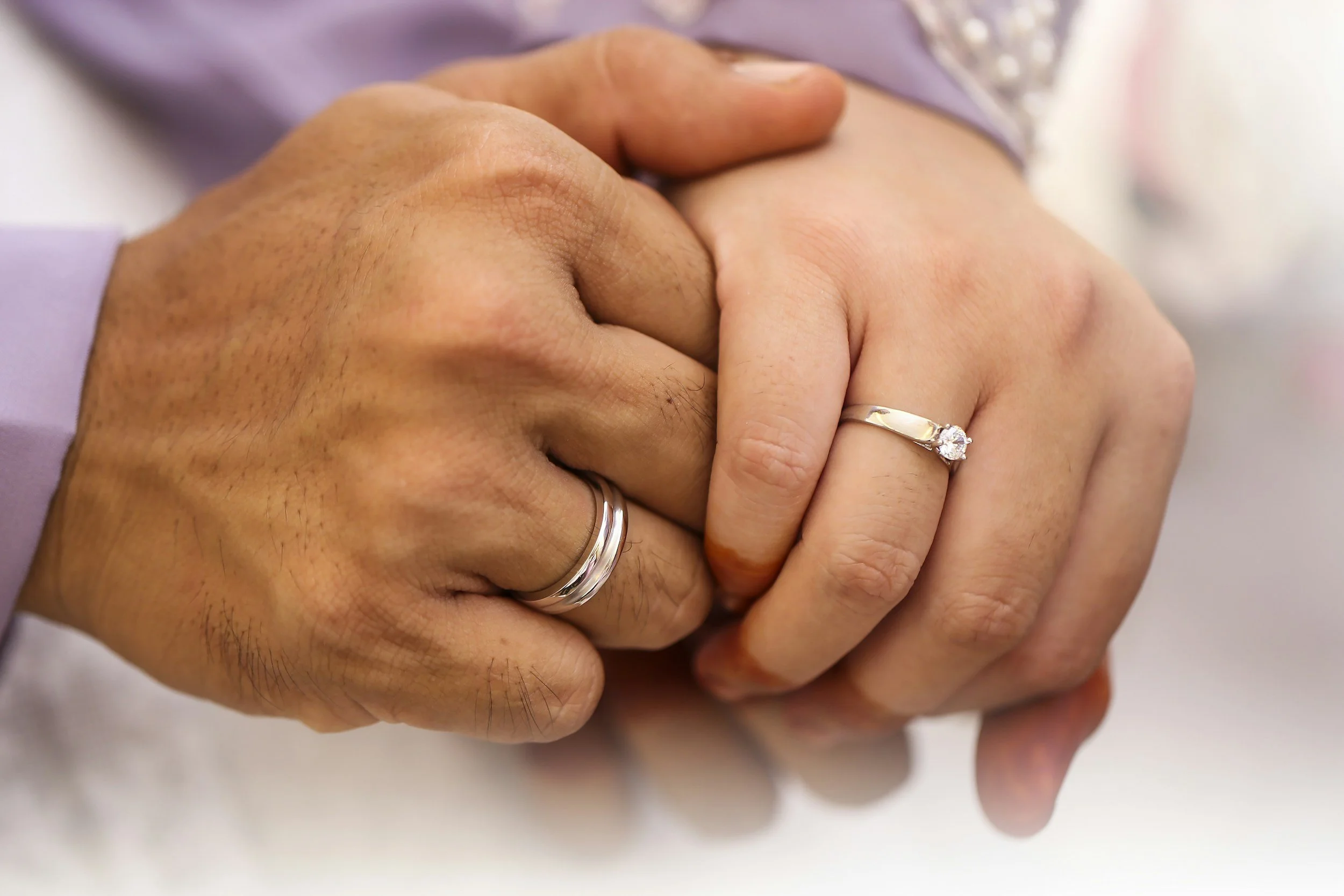 Two hands holding each other, with rings visible on the fingers.
