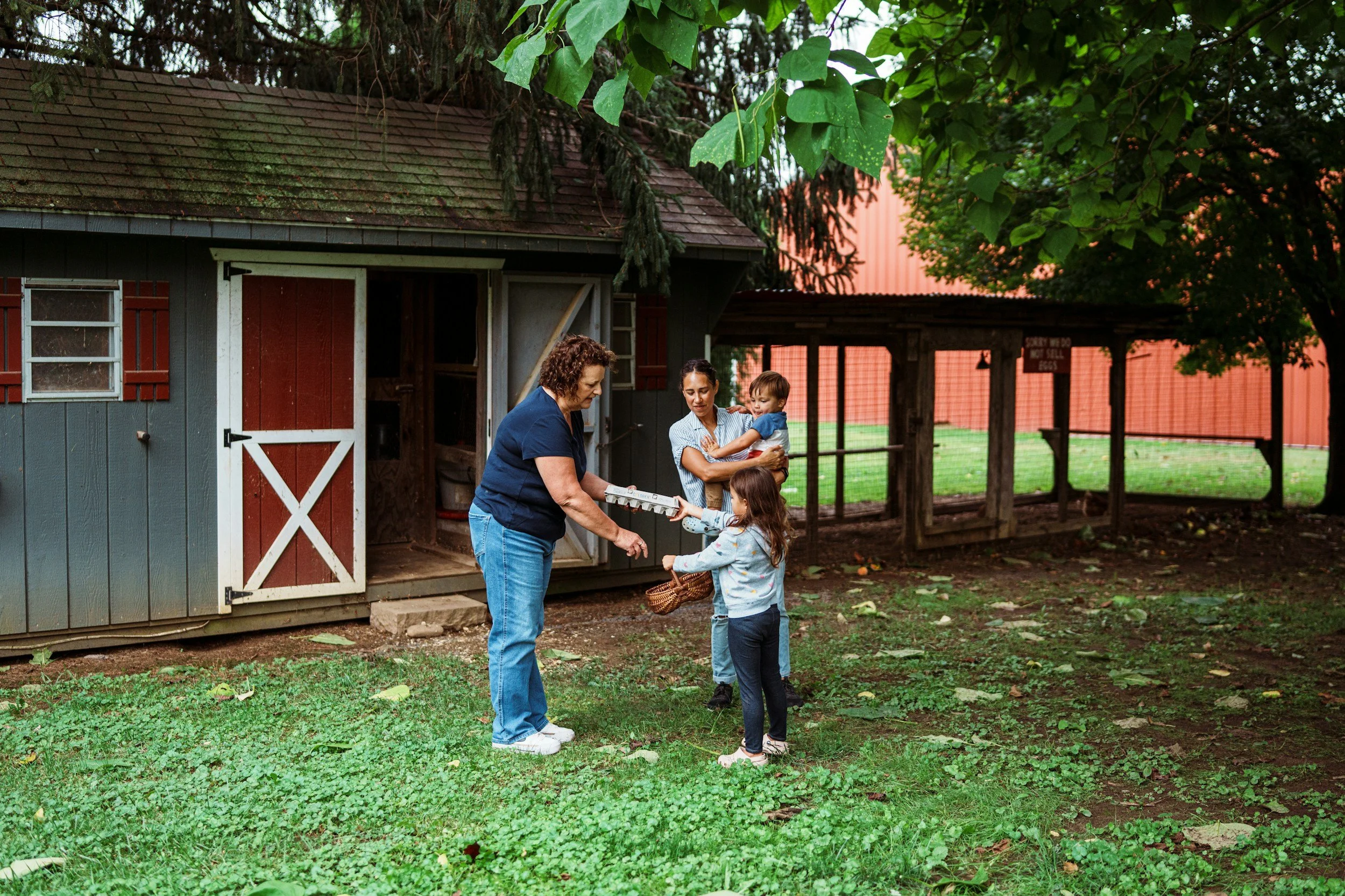Family counseling in Dallas: two women play with a young girl in a sunny backyard while one of them holds a small child.