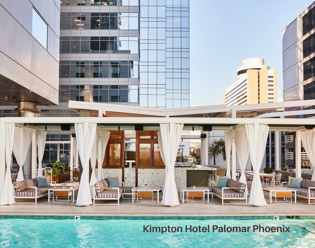 Outdoor pool area at the Kimpton Hotel Palomar Phoenix with cabanas, chairs, and a city skyline background.