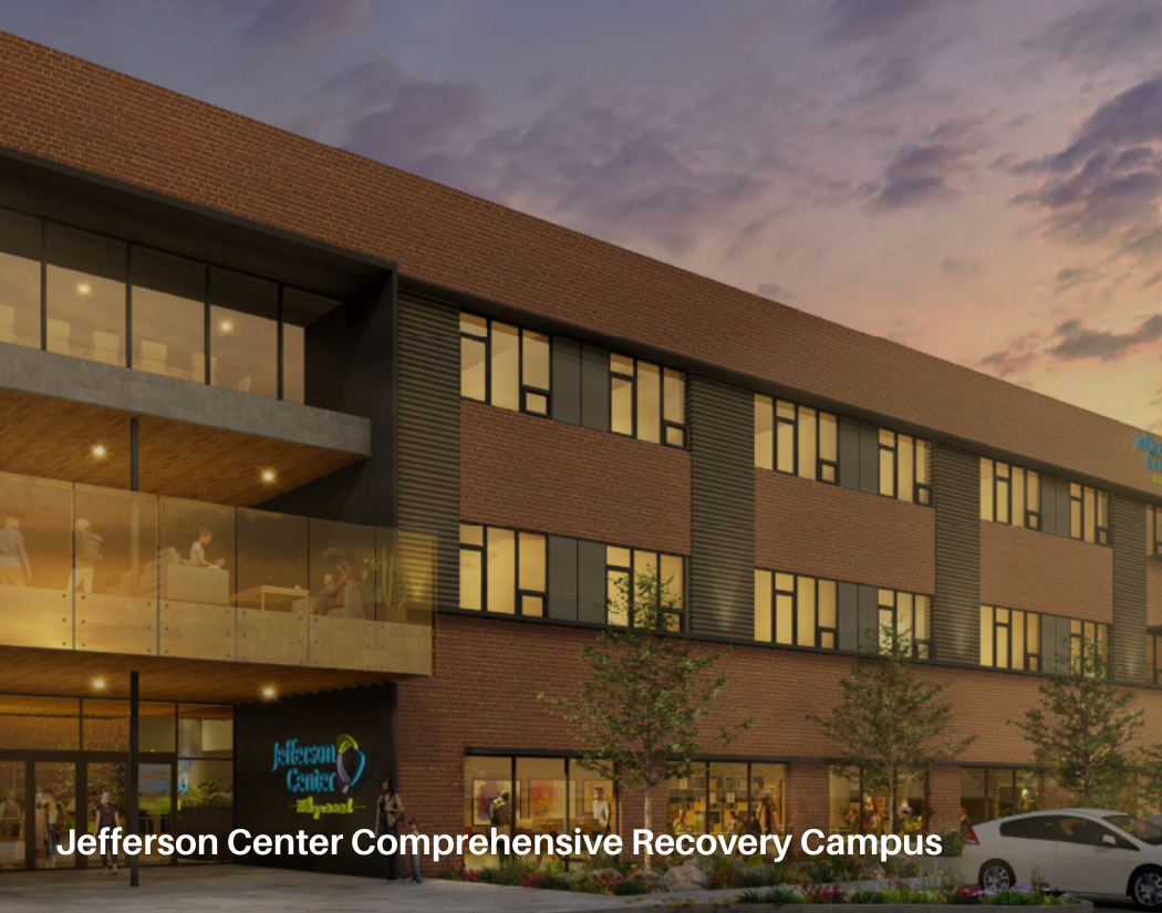 The Jefferson Center Comprehensive Recovery Campus is a modern, multi-story building with brick and glass exterior, large windows, and an entrance with people walking and cars parked outside, set against a colorful evening sky.