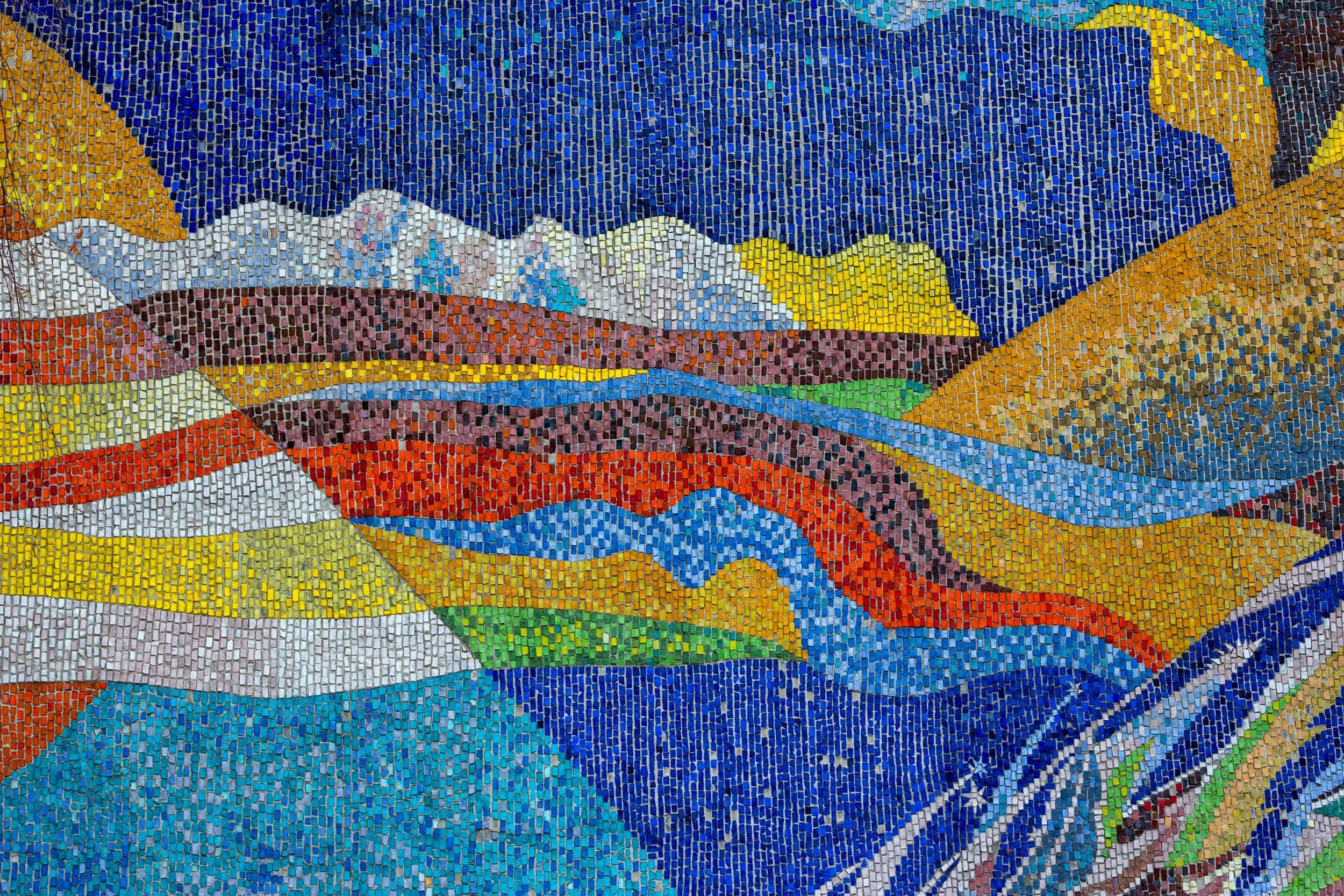 A colorful mosaic artwork depicting mountains, rivers, and valleys using small tiles in various bright colors.