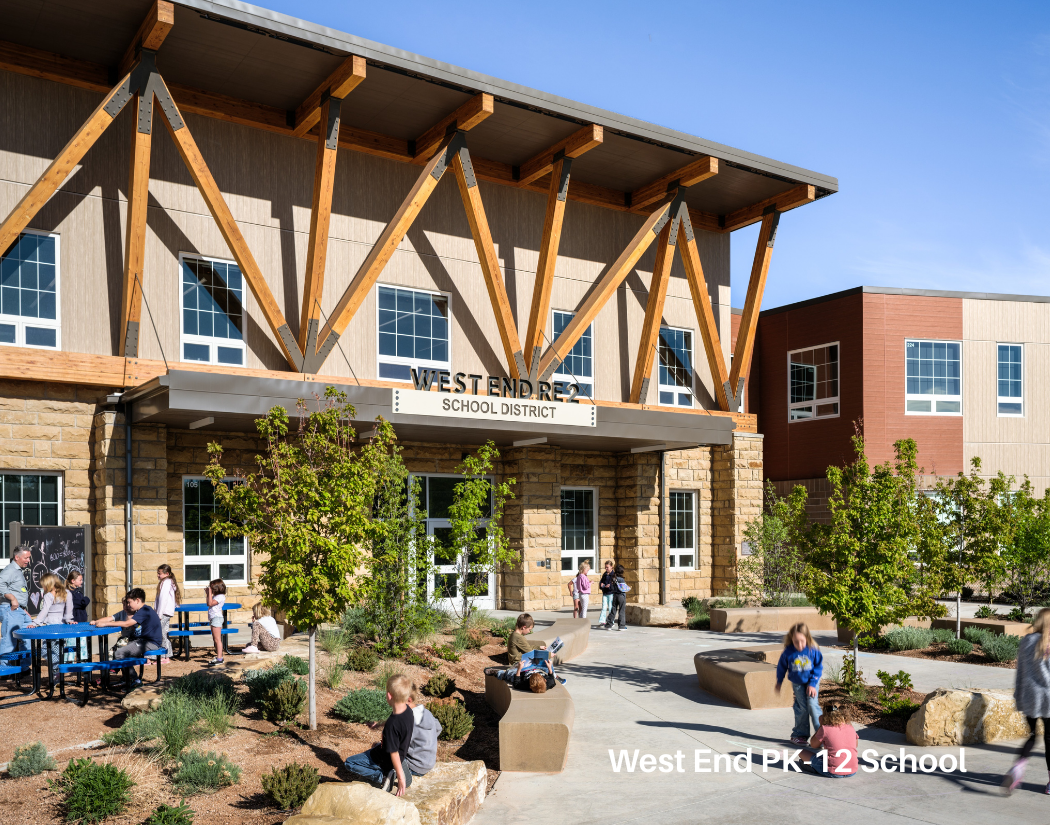 Children playing and sitting outside of West End Elementary School with modern architecture and landscaping.
