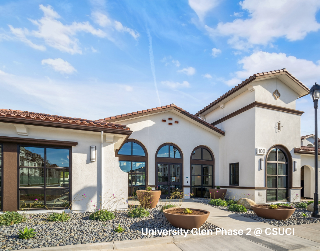 Modern building with arched windows and a landscaped front area with large planters and small plants under a blue sky.