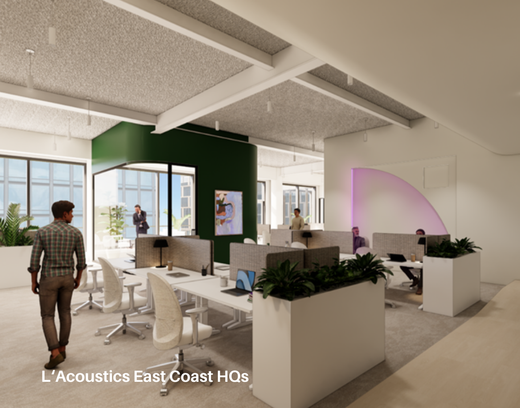 Modern open-plan office with white desks, ergonomic chairs, plants, and large windows. Several people are working or walking around, with a green accent wall and wall-mounted screens.