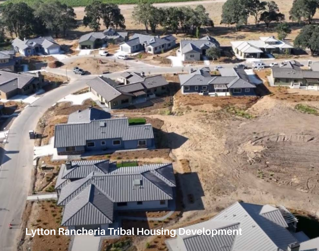 Aerial view of a housing development with multiple houses under construction in a rural area, with trees in the background.