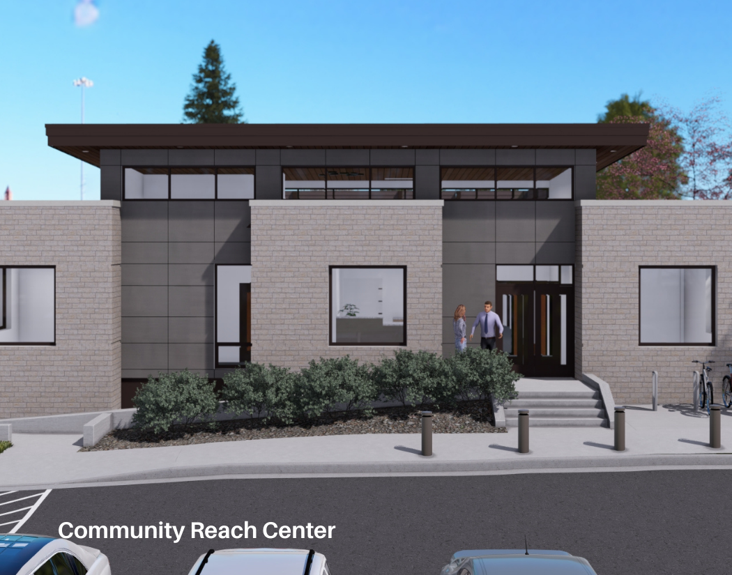 Front view of a modern building labeled 'Community Reach Center,' with two people walking up the steps, parked cars in front, and bicycles on the side. The building has large windows and landscaping with bushes.