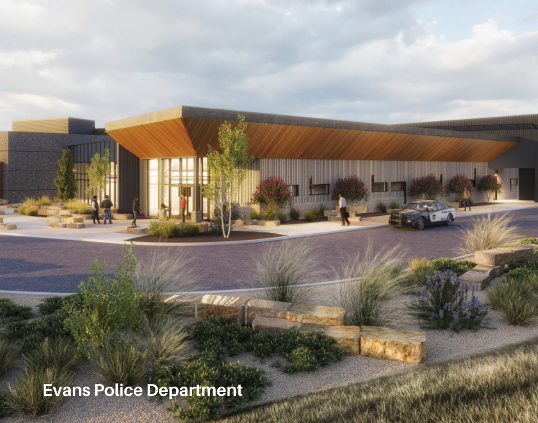 A modern Evans Police Department building with glass entrance, surrounded by landscaping, people walking, and a police car parked outside.