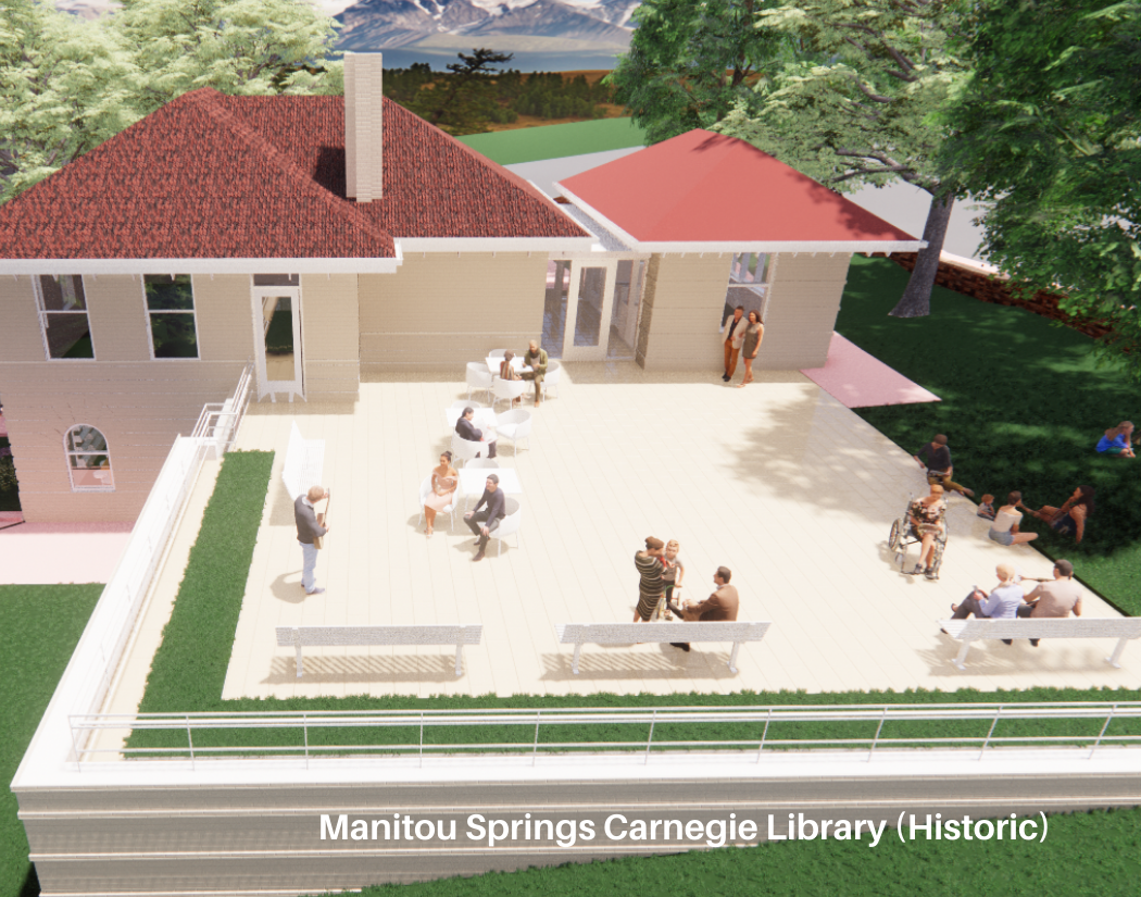 People gathered outside the Manitou Springs Carnegie Library, sitting on benches and talking, with some standing and reading near the entrance, surrounded by trees and a grassy area.