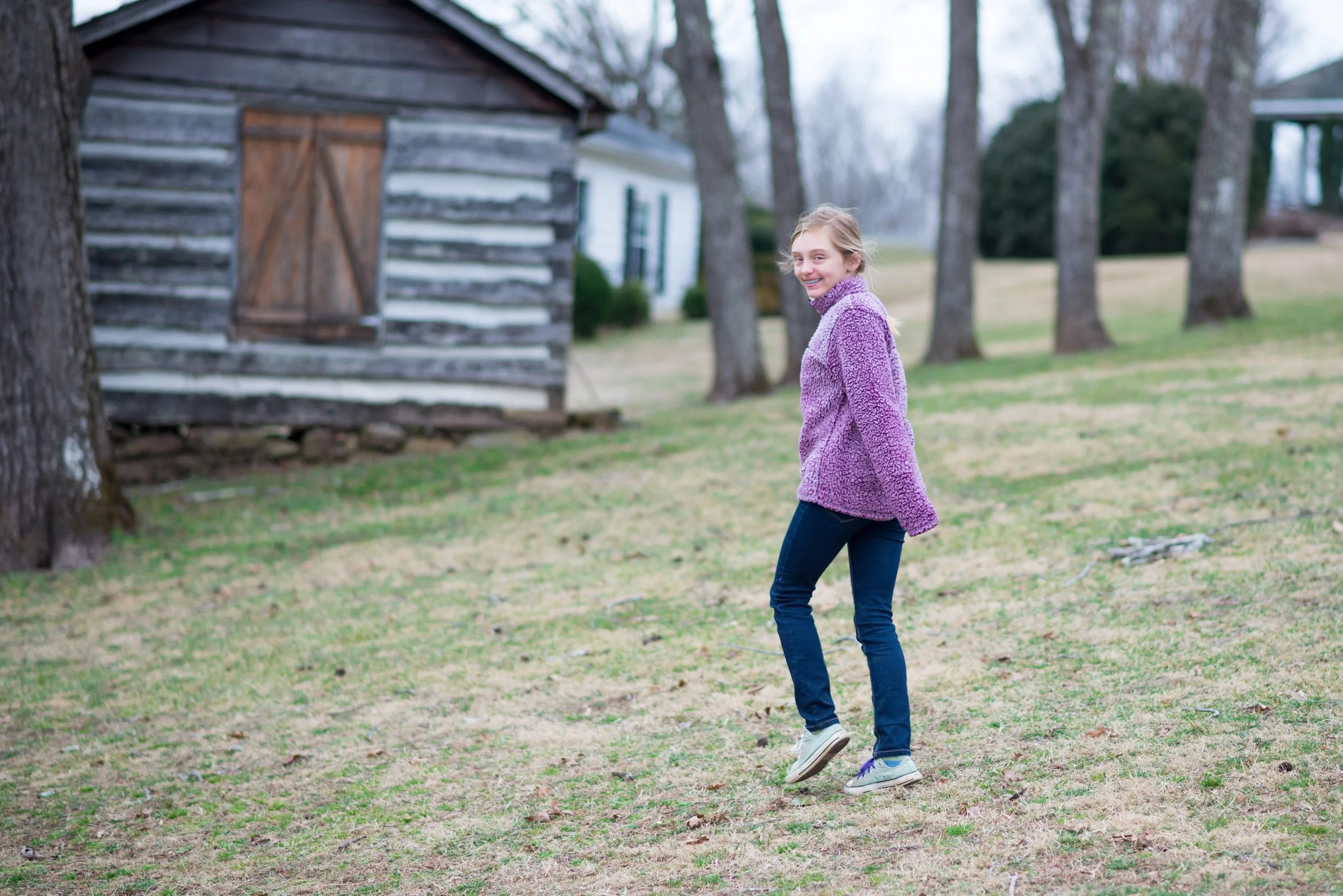 Oakland student explores campus near a log cabin.
