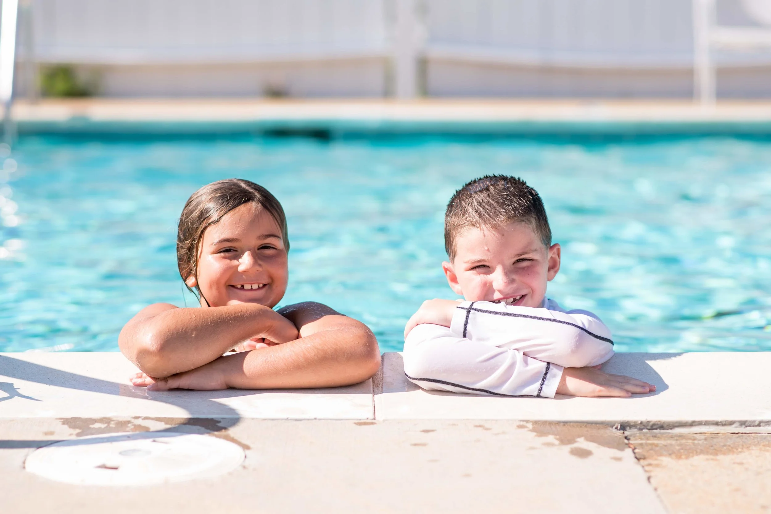 Two campers smiling at the side of the pool.