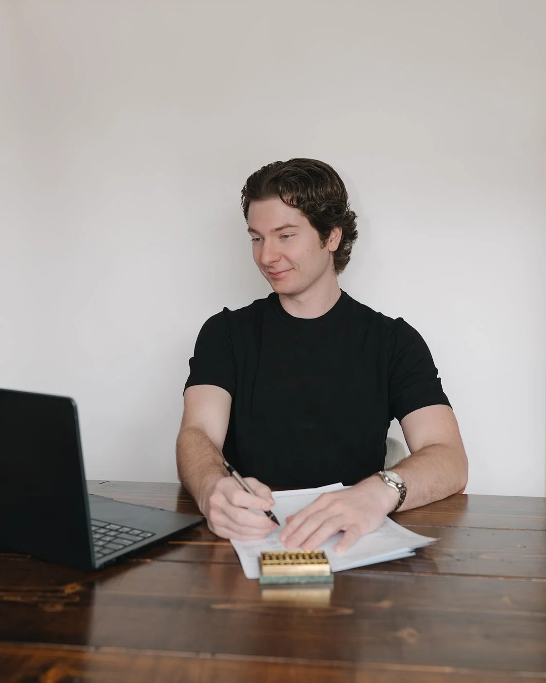 A smiling, independent bookkeeper working at his desk with a laptop and abacus in front of him.