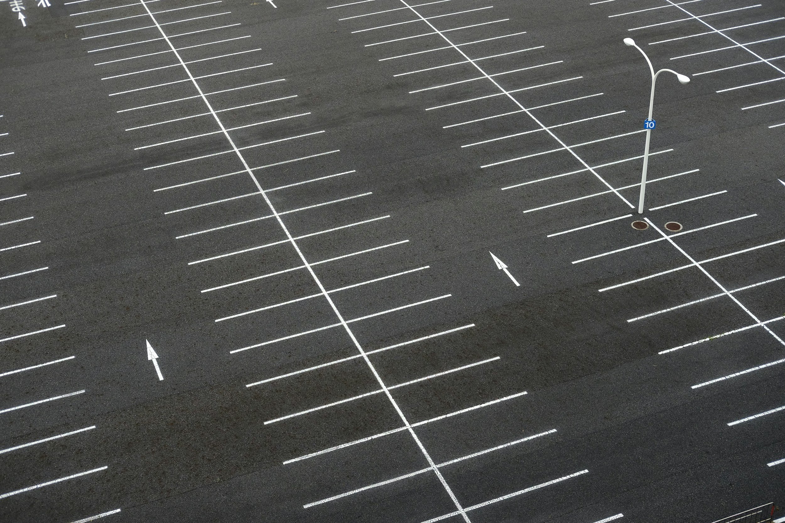 Empty parking lot with numbered spaces, directional arrows, and a streetlamp.
