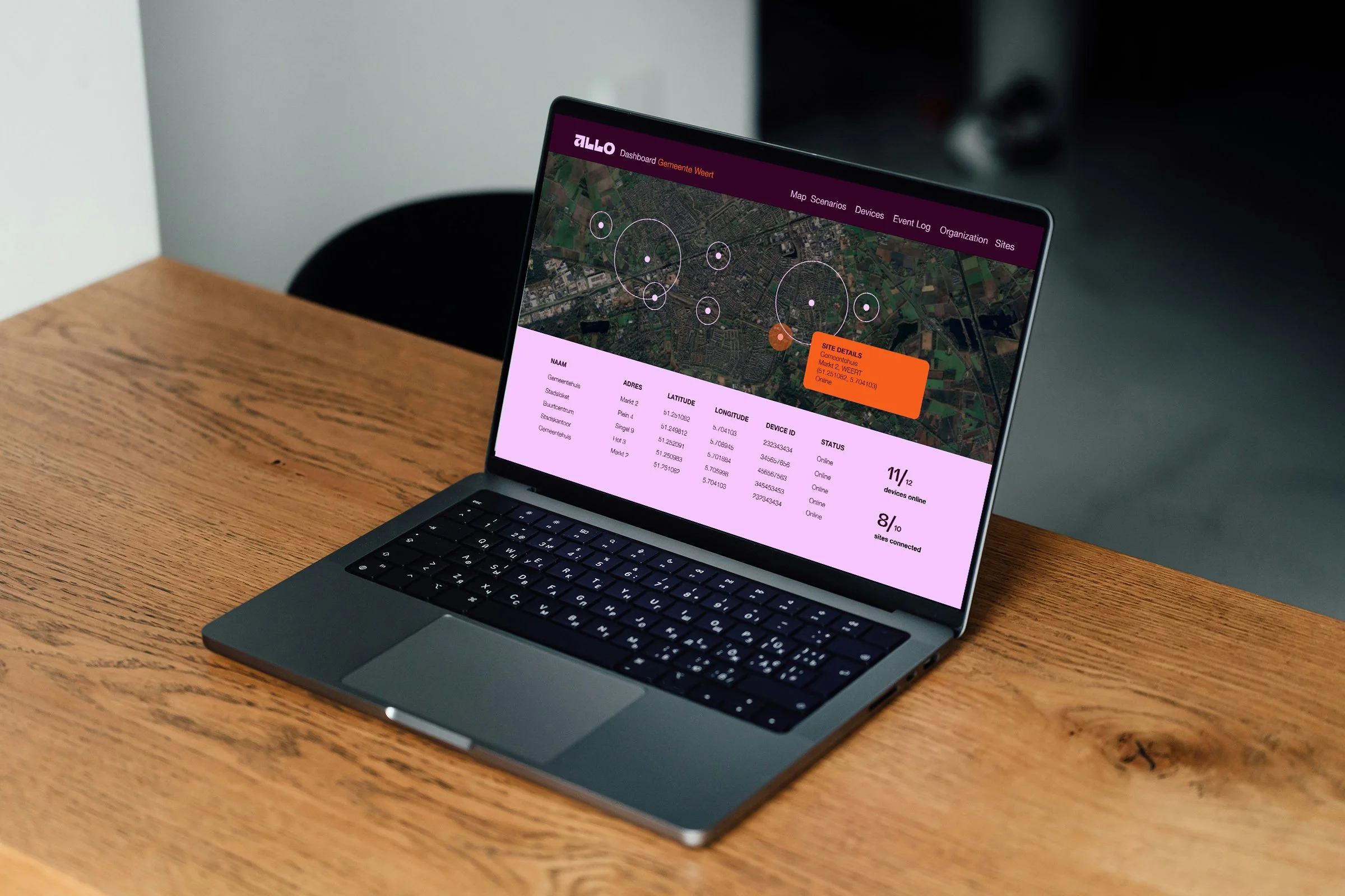 A laptop on a wooden table displaying a map with data points and site details on the screen.