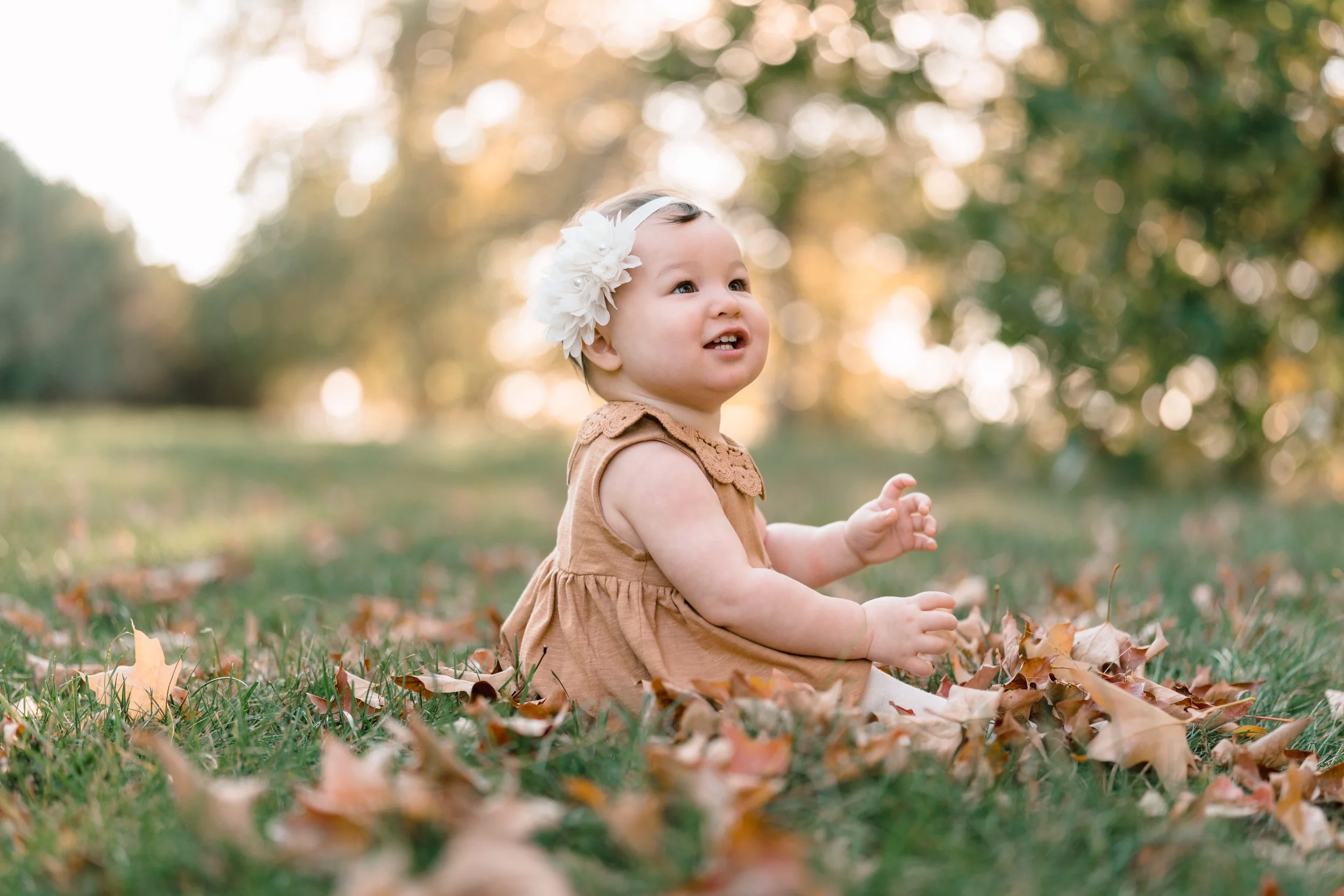 Child smiling among colourful autumn leaves during an Ottawa fall mini session