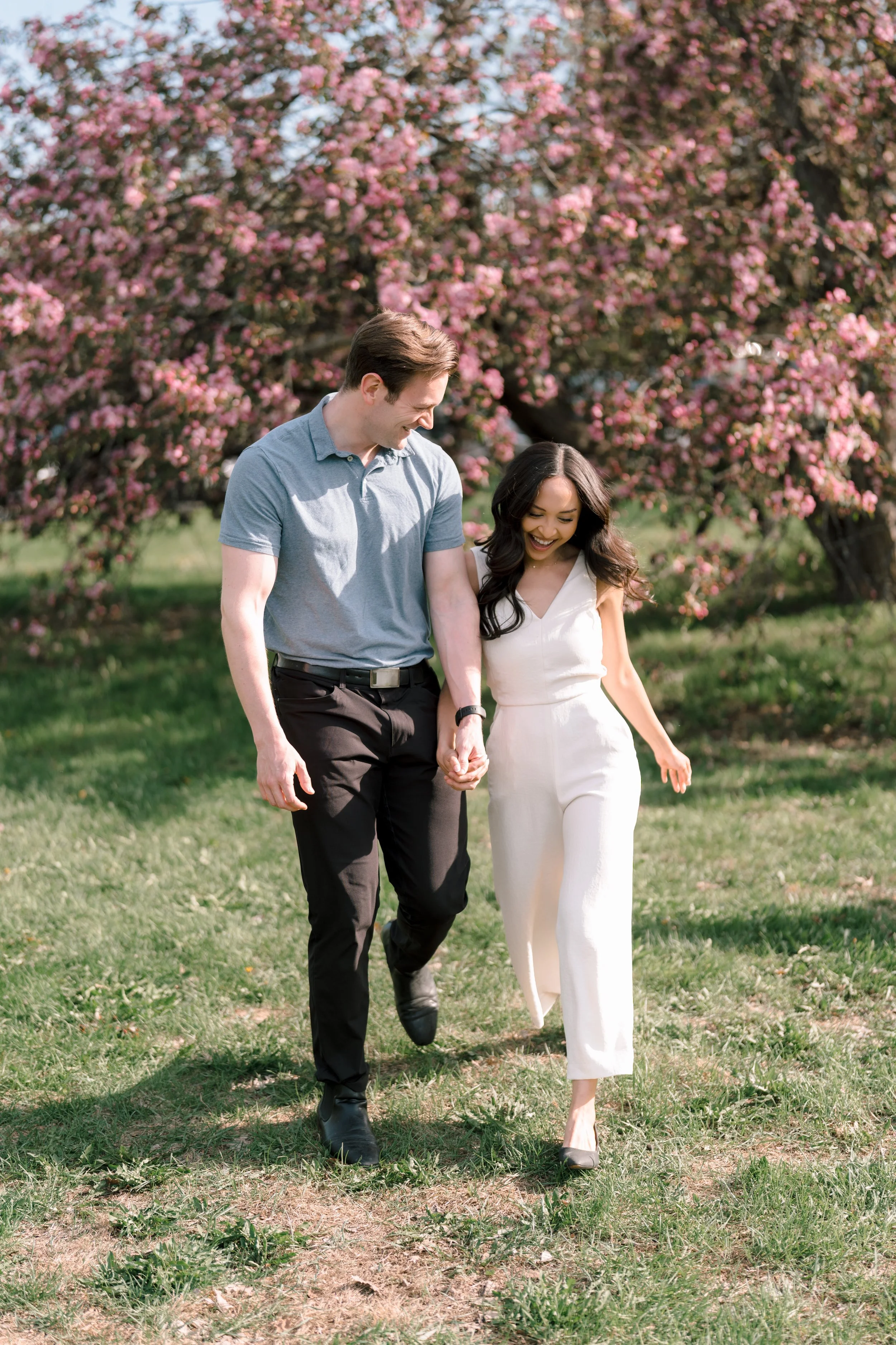 Couple walking beneath blooming trees during an Ottawa spring mini session with Palm Tree Studio