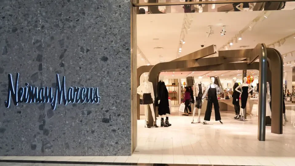 The entrance to a Neiman Marcus store with mannequins dressed in fashion apparel inside the store.