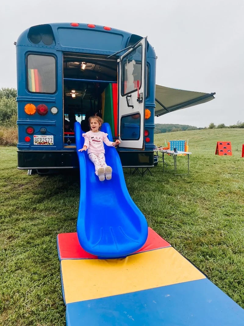 a young girl sliding down a slide on the we rock the spectrum sensory safe bus in harford county maryland