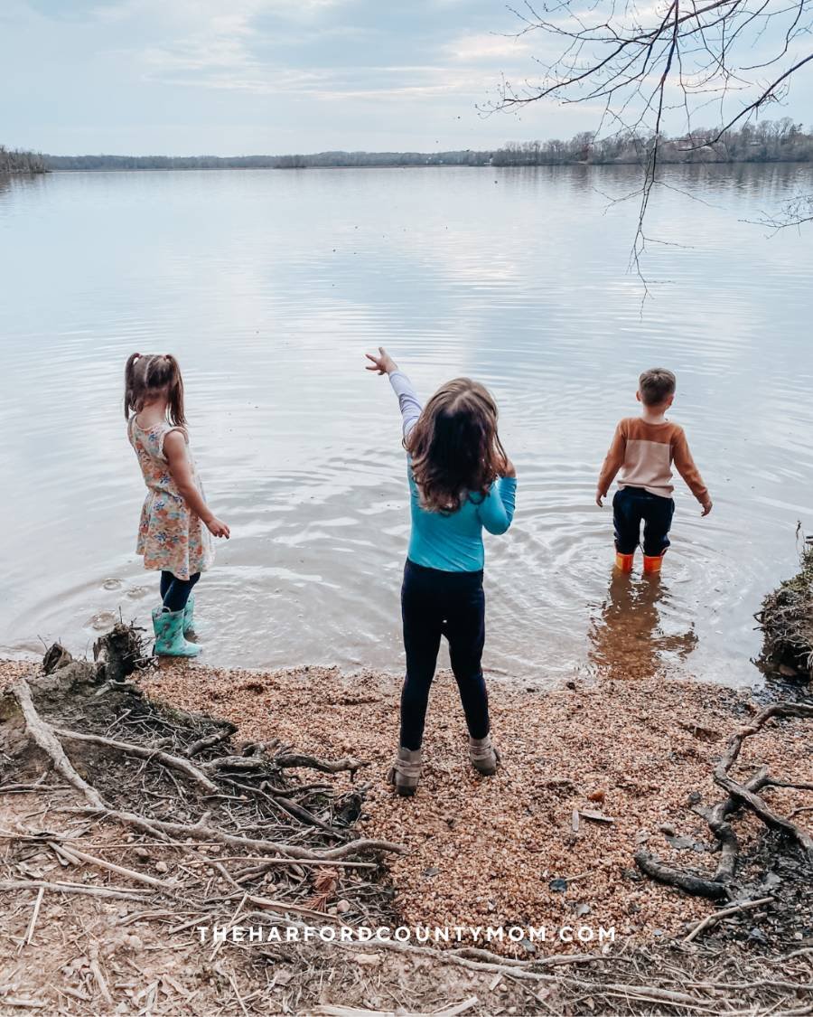 3 small children wade in water on edge of Anita C. Leight Estuary Center sensory trail in Abingdon, Maryland