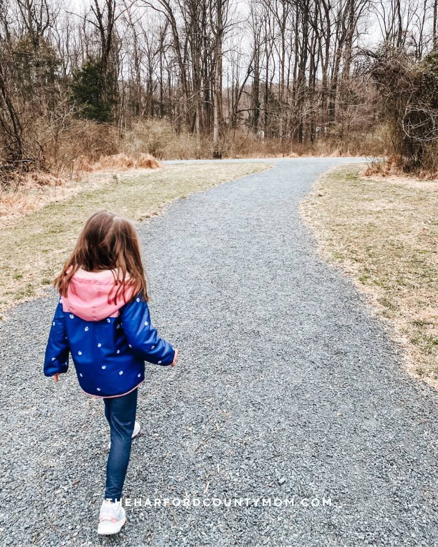 Girl in jacket walks along flat, gravel loop trail at Emily Graham Bayless Park in Bel Air, Maryland