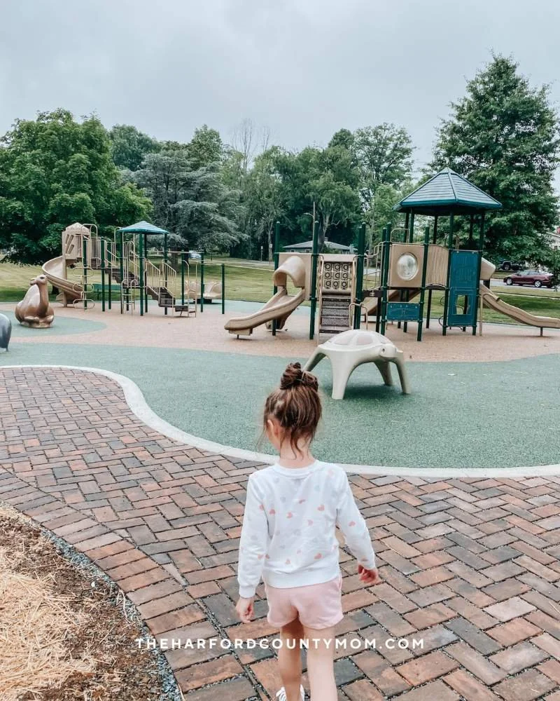 Girl walks toward Shamrock Park playground in Bel Air, MD near the Bel Air Library and downtown
