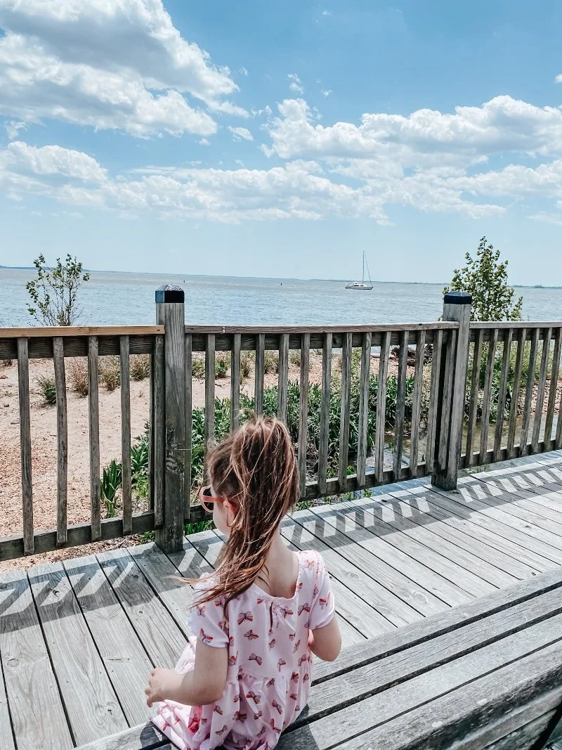 girl sitting on a bench while walking the promenade in downtown havre de grace