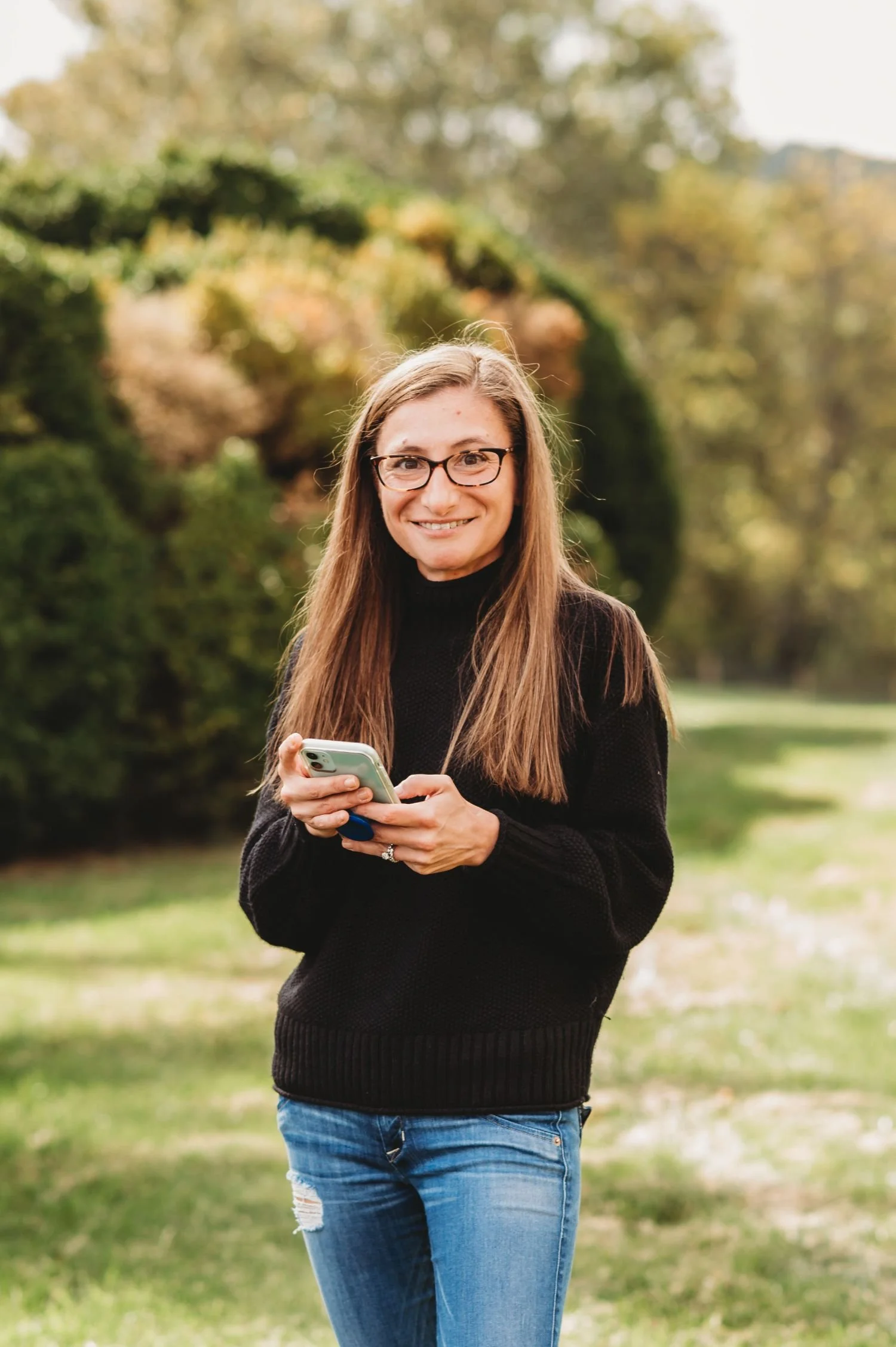 Ange smiling at camera while on her phone representing how to work with her for social media marketing