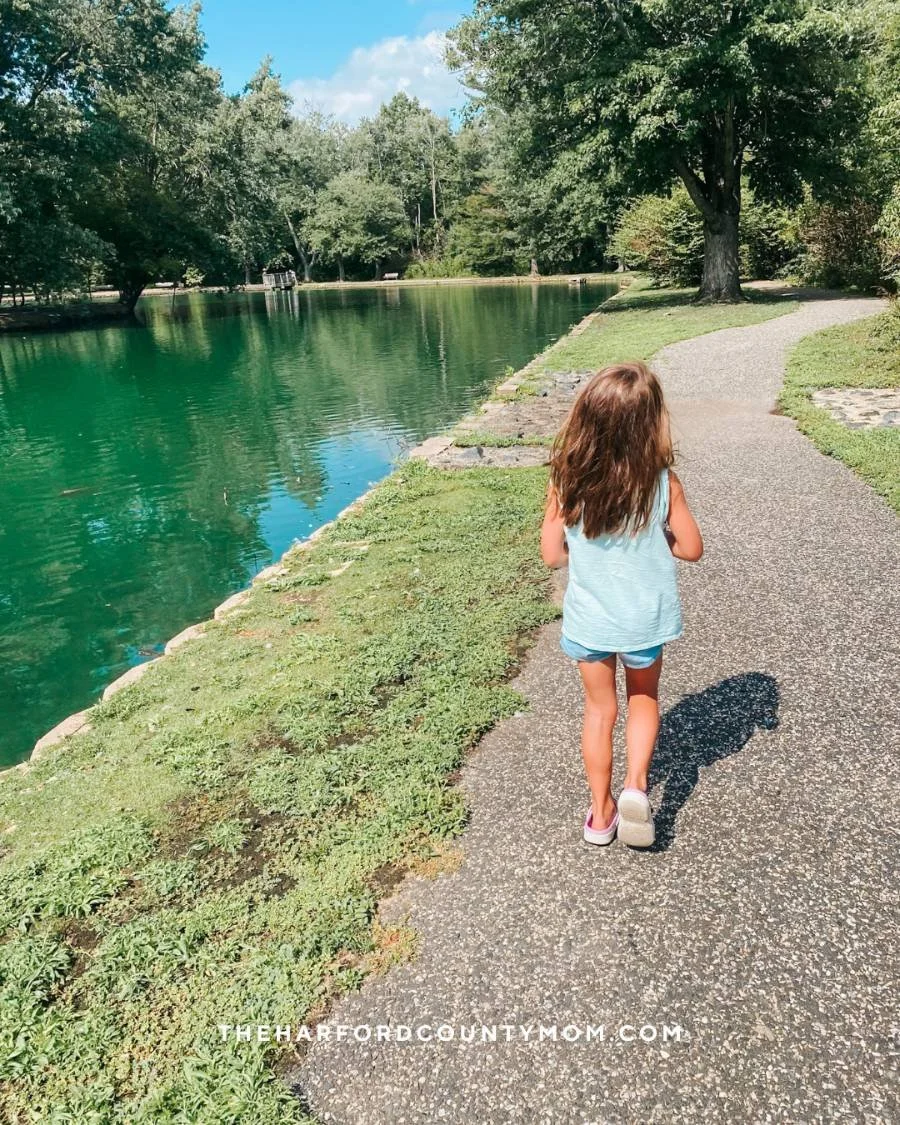 Girl walks on paved loop trail along Bynum Run at Bynum Run Park in Bel Air, Maryland. Perfect for spotting turtles, ducks, and geese