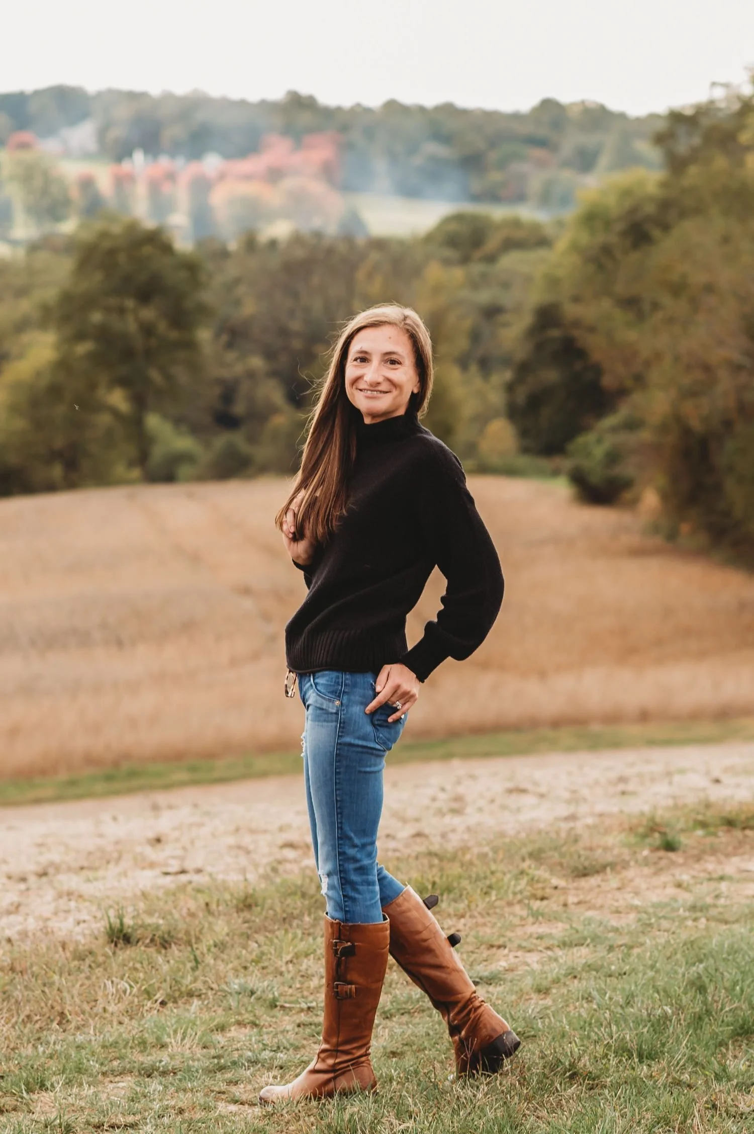 The Harford County Mom stands in rural farmscape with rolling hills behind her