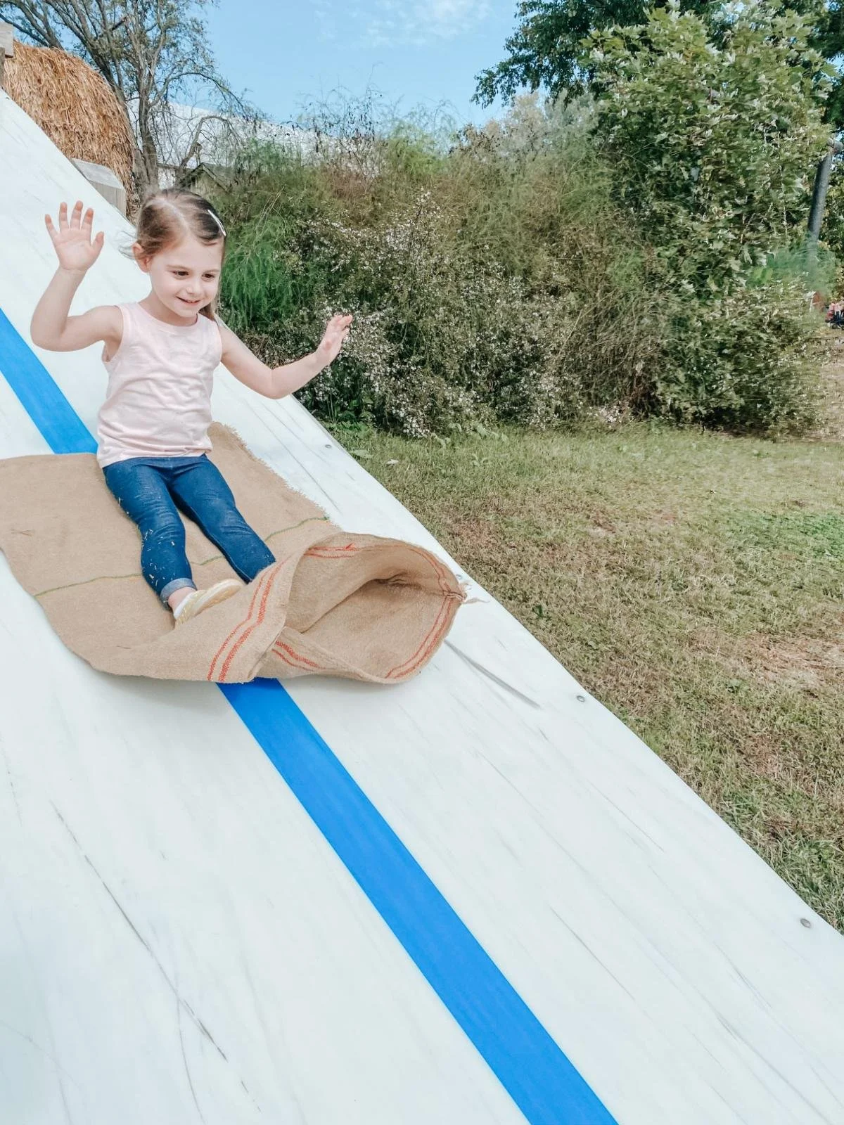 girl on slide sitting on burlap sack during a seasonal festival in Harford County
