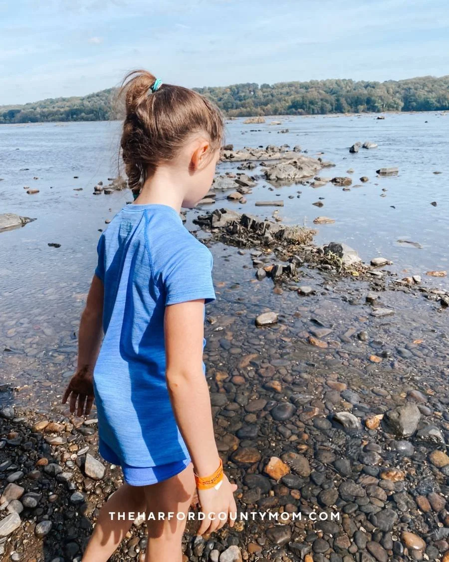 girl walks in rocky, shallow water along the Susquehanna State Park trail in Havre de Grace, Maryland. This trail is perfect for waterfront views and sandy areas for play