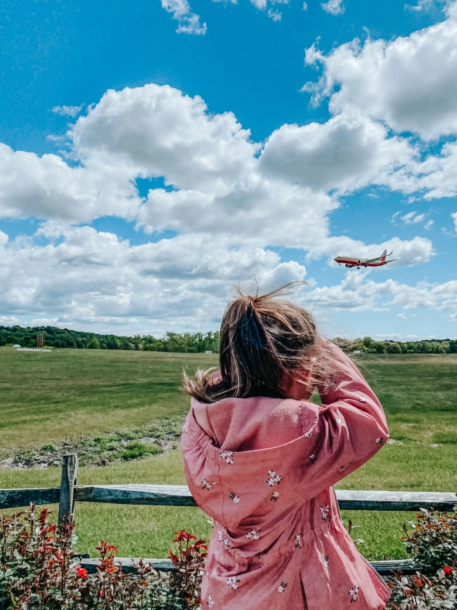 Girl in pink jacket looks out to watch an airplane land at BWI Airplane Park in Anne Arundel County, Maryland