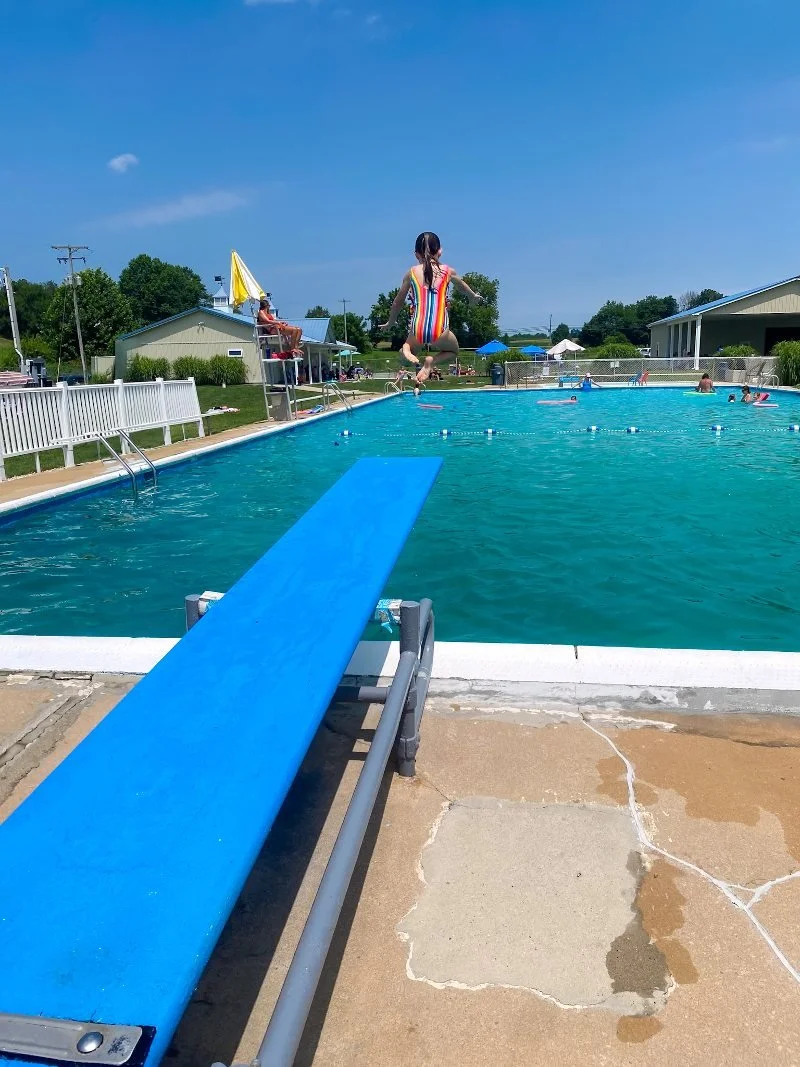 girl jumping off a diving board and into shanberger's pool in fawn grove, pennsylvania