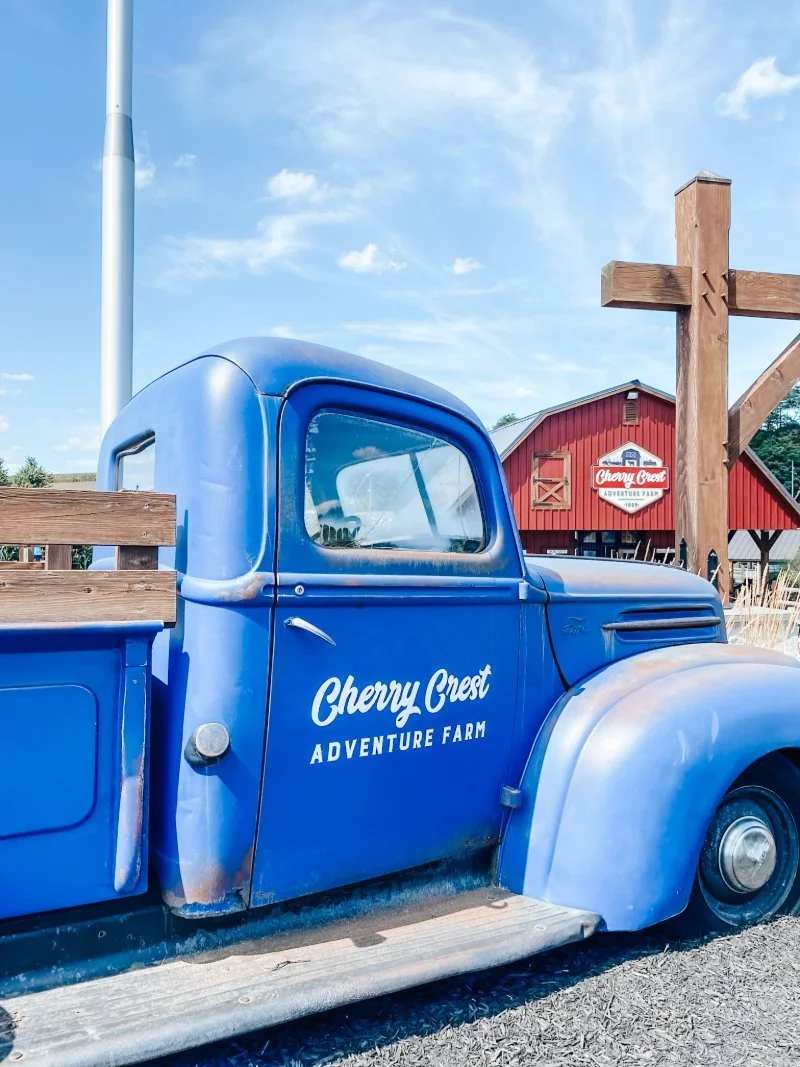 An old blue truck with "Cherry Crest Adventure Farm" written on the door. The perfect fall adventure for families with a corn maze, pumpkin patch, and over 60 kids activities