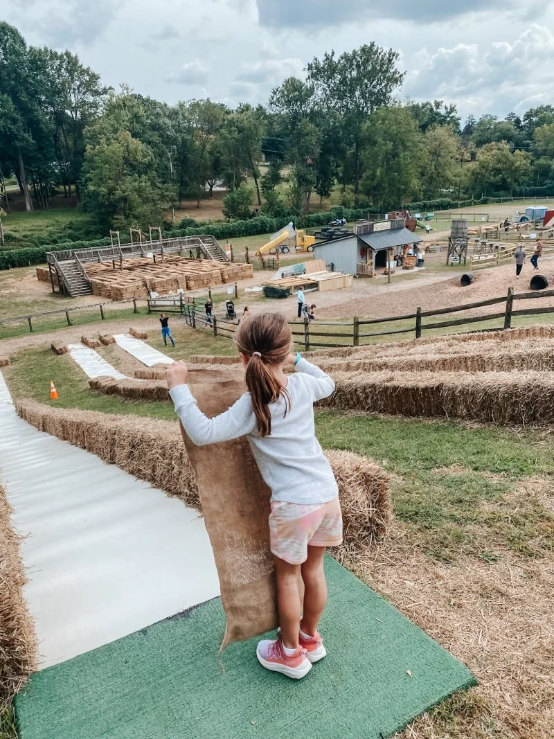 Young girl gets ready to slide down hill on a burlap sack at Weber's Farm in Parkville, Maryland. It's one of many activities for kids this fall