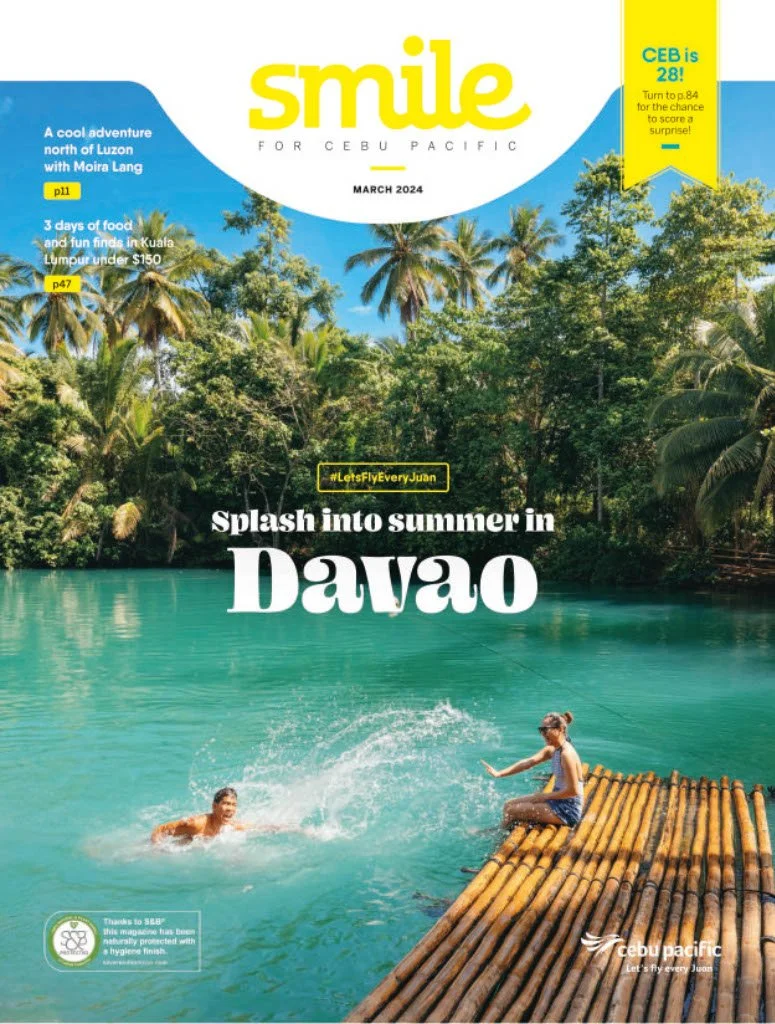 Magazine cover titled 'Smile for Cebu Pacific' featuring a tropical Davao scene with two children playing in turquoise water near a bamboo raft surrounded by lush green trees and tall palm trees under a blue sky.