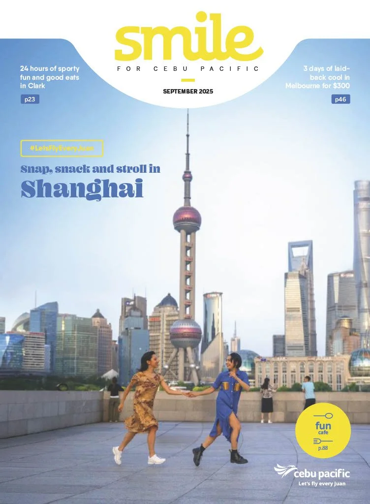 Two women holding hands and playing in front of the Shanghai skyline, including the Oriental Pearl Tower.