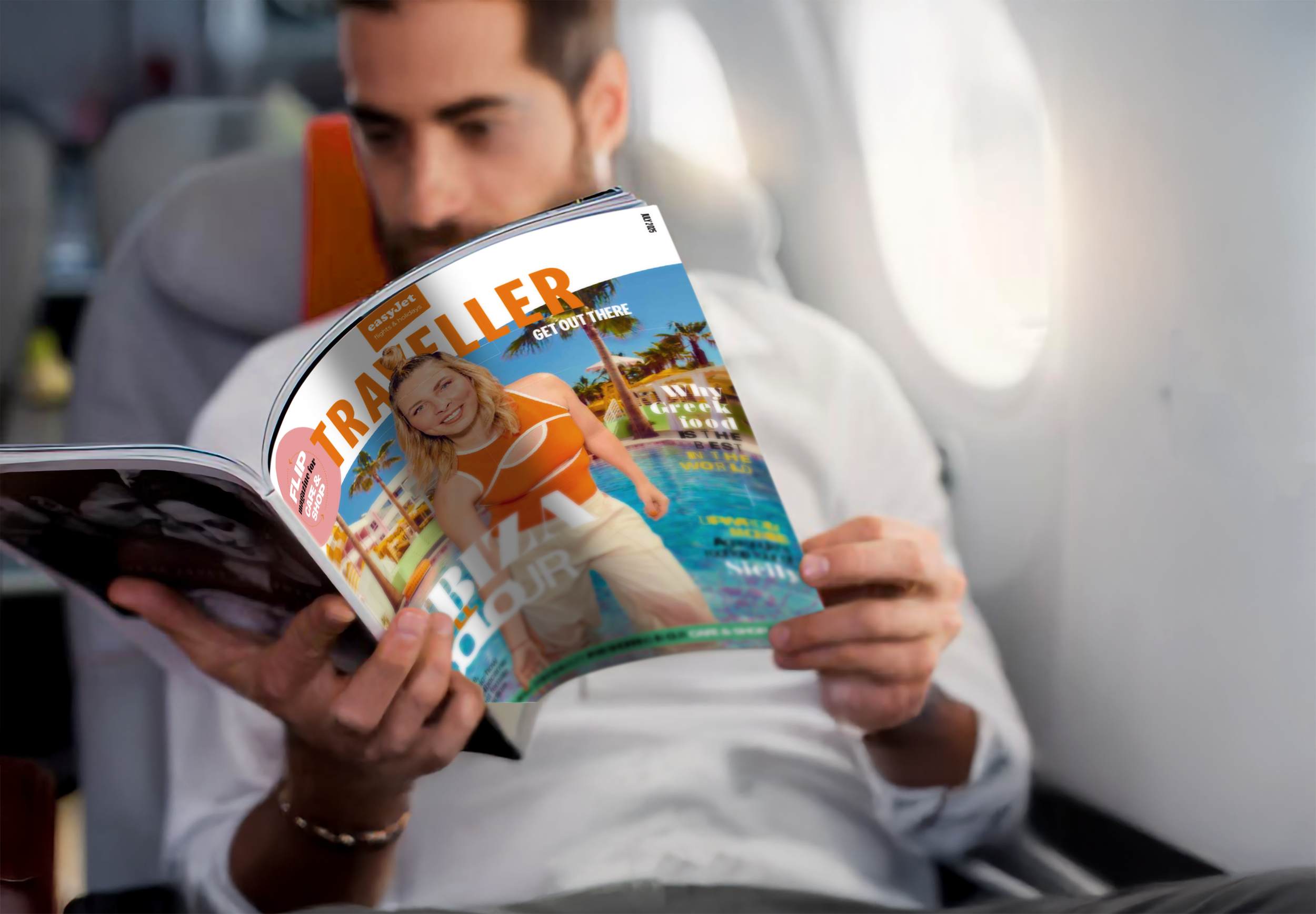 A man sitting on an airplane reading a travel magazine with a colorful cover featuring a smiling woman in an orange swimsuit in front of a tropical resort with palm trees and a swimming pool.