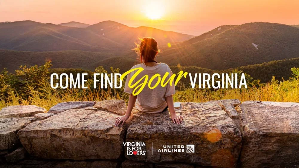A woman sitting on large rocks overlooking a mountainous landscape at sunset in Virginia, with text overlay saying "Come Find Your Virginia" and logos of Virginia is for Lovers and United Airlines.