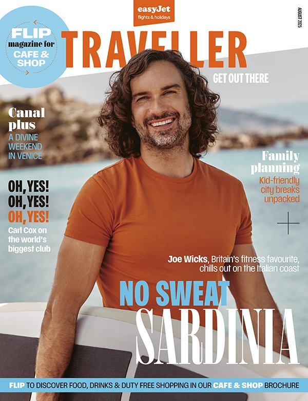 Magazine cover featuring a man with long curly hair, smiling, wearing an orange T-shirt, in front of a beach background with rocks and water. Headlines include travel and leisure topics.