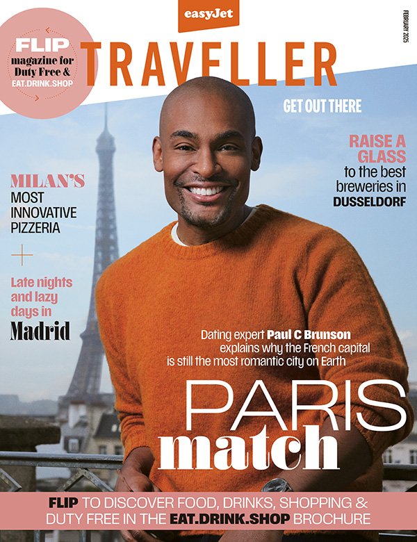 Cover of EasyJet Traveller magazine featuring a smiling man in an orange sweater with the Eiffel Tower in the background. Headlines mention food, drinks, travel destinations like Milan, Madrid, and Dusseldorf, and a feature on Paris.