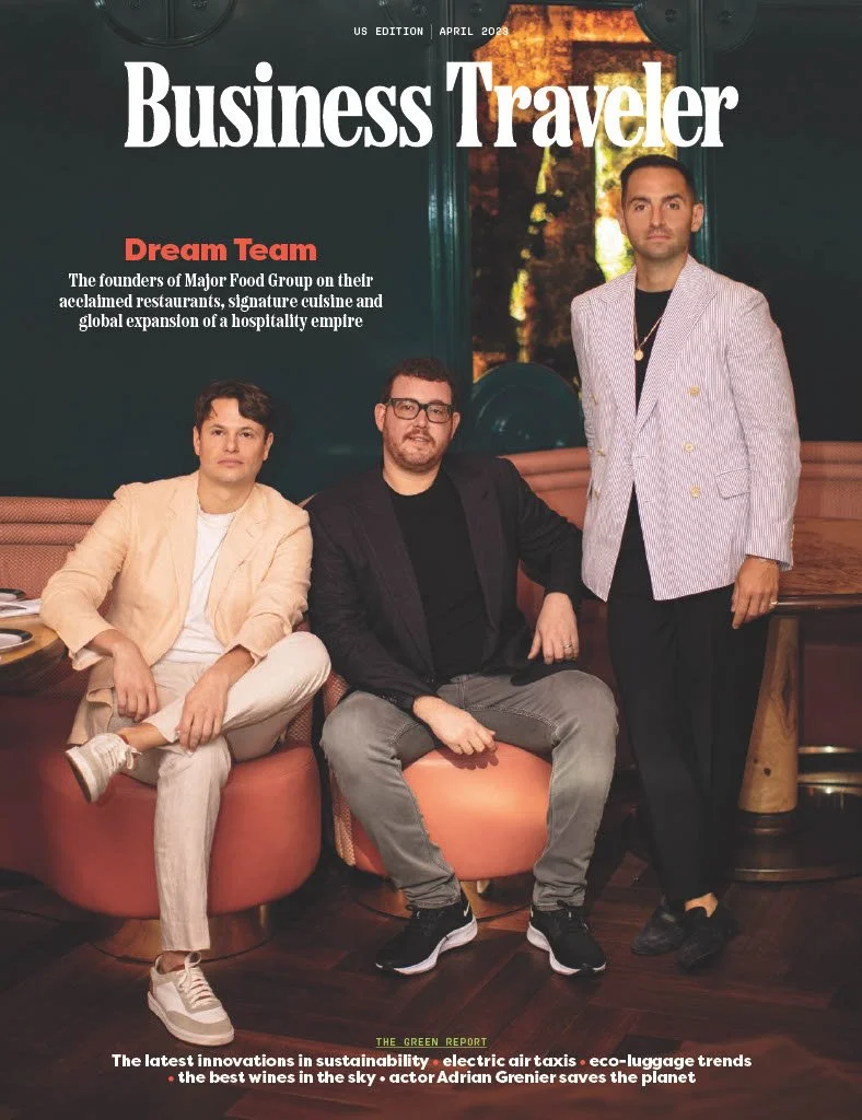 Cover of Business Traveler magazine, April 2023 issue, featuring three men in a restaurant or lounge setting, with the headline 'Dream Team' and text about the founders of Major Food Group, sustainability, electric air taxis, eco-luggage trends, and actor Adrian Grenier.