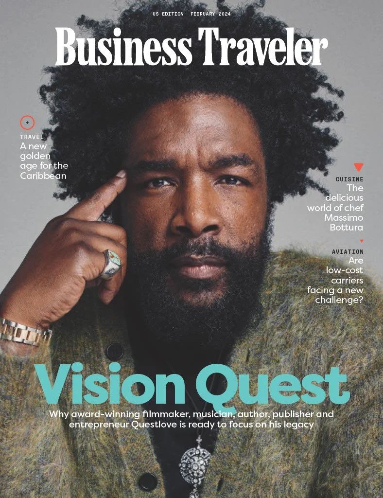 The cover of Business Traveler magazine, February 2024 issue, featuring a close-up portrait of a man with dark skin, a beard, and curly black hair. He is touching his temple and wearing a ring and a watch. The main headline reads 'Vision Quest,' highlighting a profile of Questlove, an award-winning filmmaker, musician, author, publisher, and entrepreneur.
