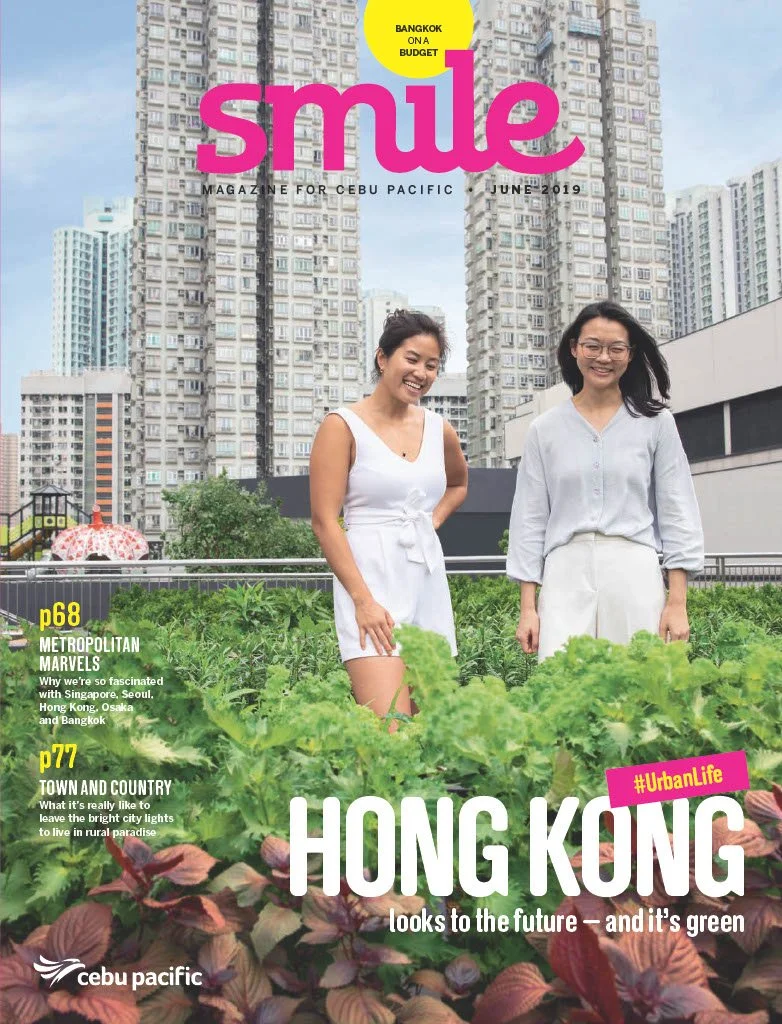 Cover of Smile magazine featuring two women in white clothing standing in a rooftop garden with green leafy plants, tall city buildings in the background, and a blue sky.