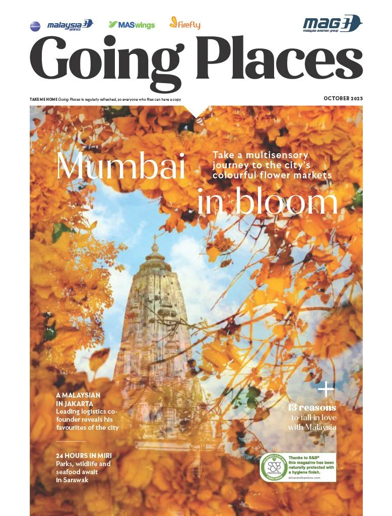 Magazine cover titled "Going Places" for October 2023, featuring an autumn scene with orange flowers and a tall monument, promoting travel in Mumbai, India with articles on Jakarta, Miri, and reasons to love Malaysia.