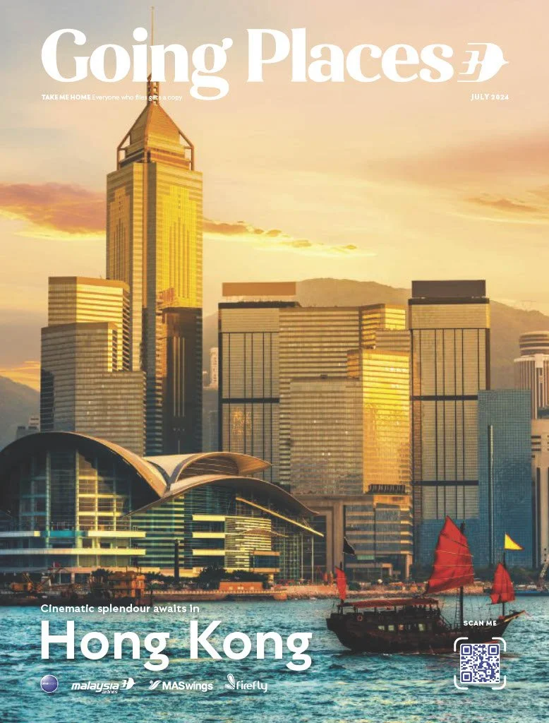 Hong Kong skyline at sunset with high-rise modern buildings, a boat with red sails in the water, and a futuristic building with a rounded roof in the foreground, promotional text for Going Places magazine, July 2024.