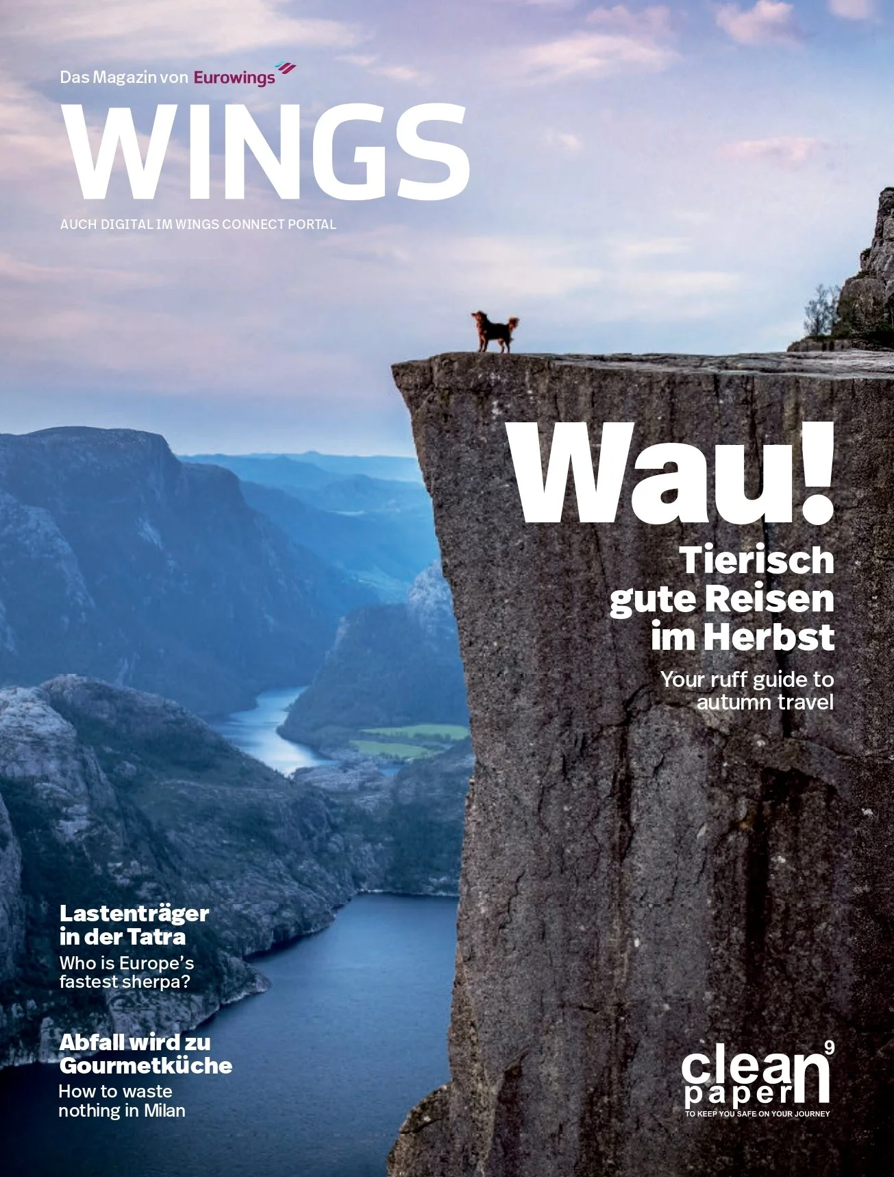 Magazine cover showing a dog on the edge of a cliff overlooking a river and mountains, with large white text saying 'WAU! Tierisch gute Reisen im Herbst' and smaller text referencing travel and environmental topics.