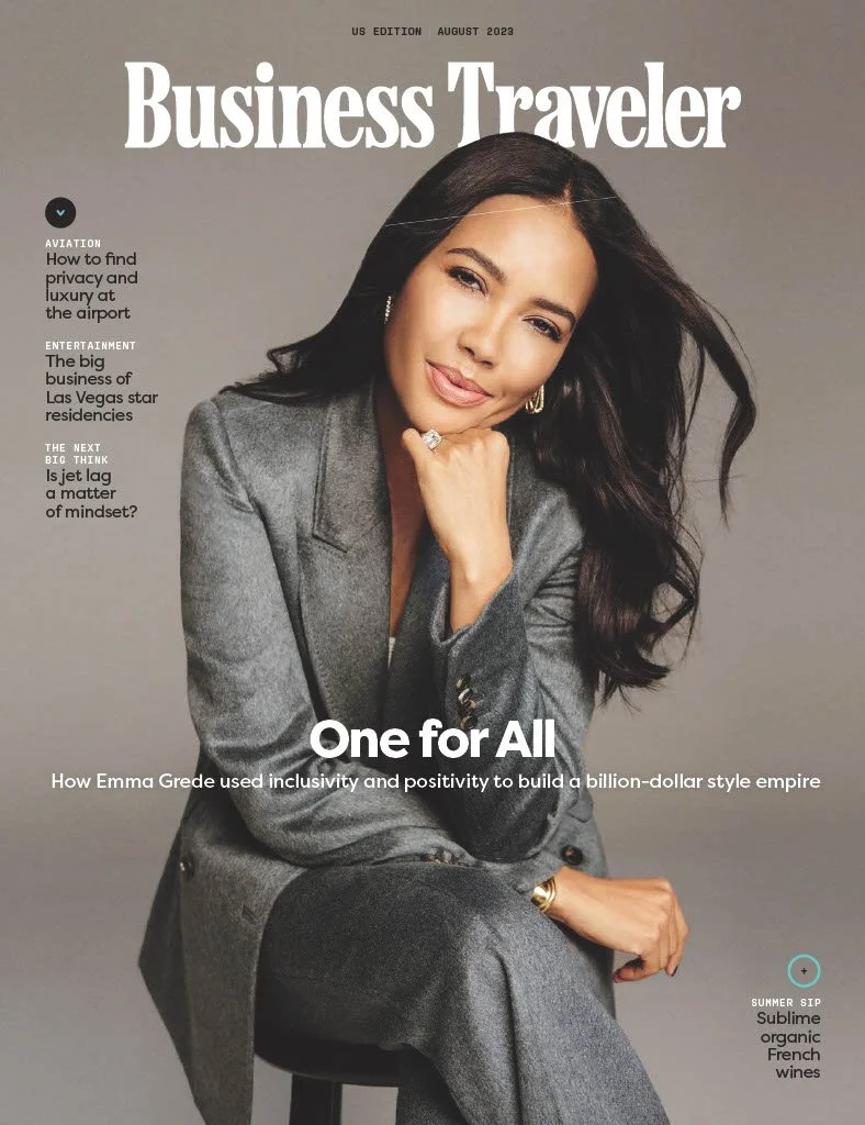 Cover of Business Traveler magazine, August 2023 issue, featuring Emma Grede smiling and sitting on a stool in a gray suit with a gray background.